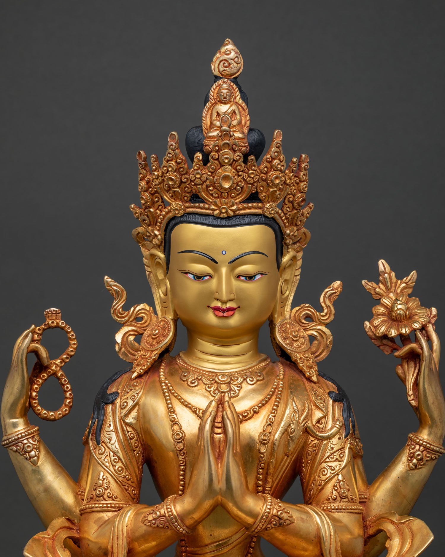 Close-up of four-armed Chenrezig holding crystal rosary, lotus flower, and wish-fulfilling gem