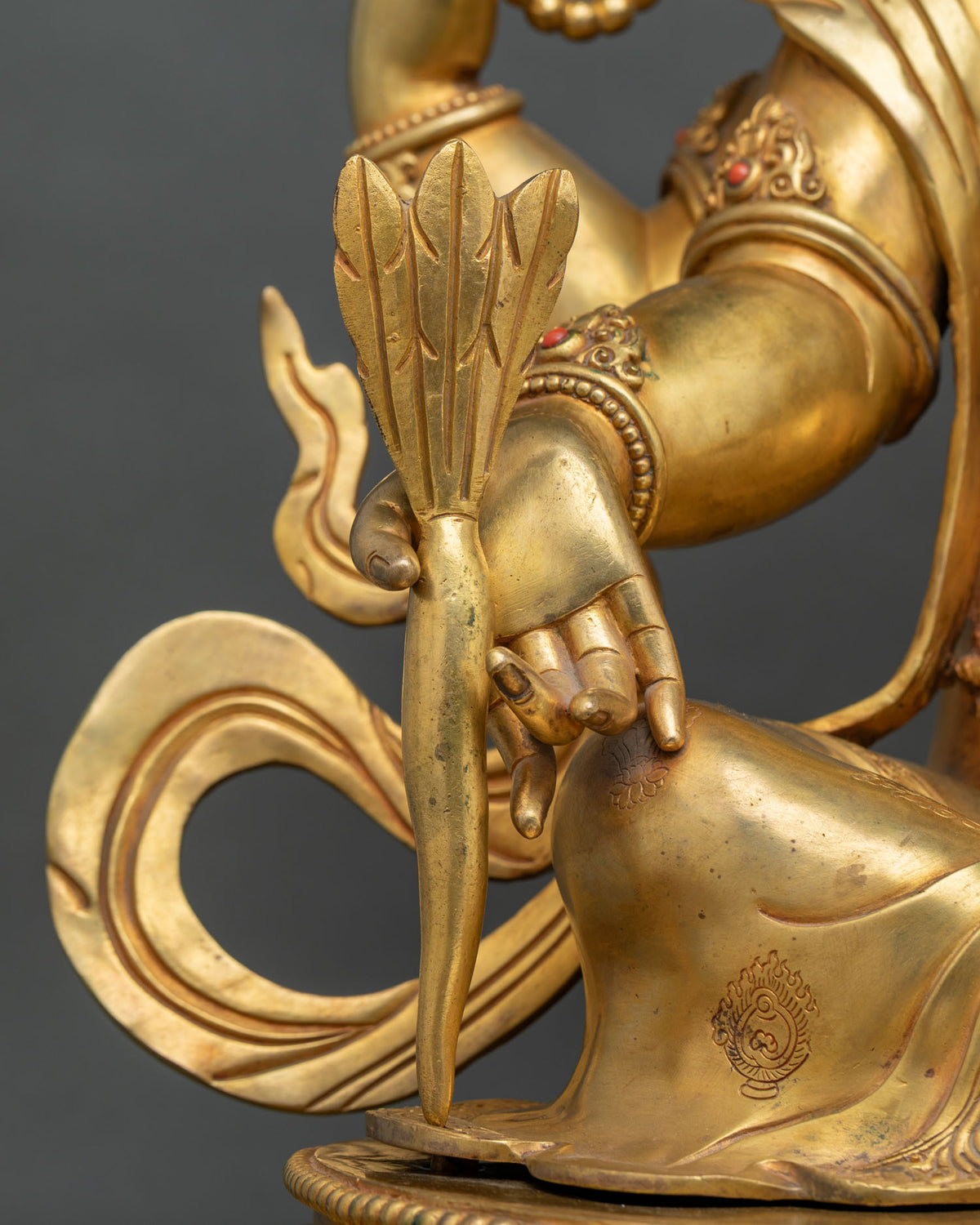 Close-up of Ganesh hand holding a tusk, symbol of abundance, on a gold fire-gilded copper statue