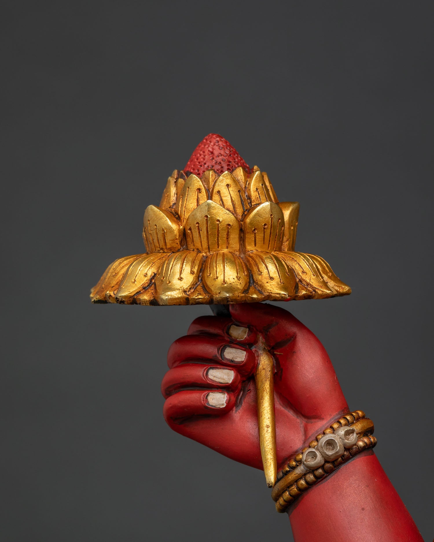 Close-up of Ganesha statue hand holding gold lotus flower, Newari repousse work