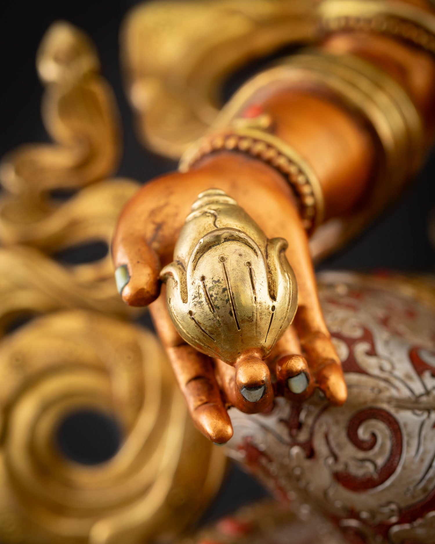 Close-up of gold-gilded citron fruit held by Yellow Dzambhala statue