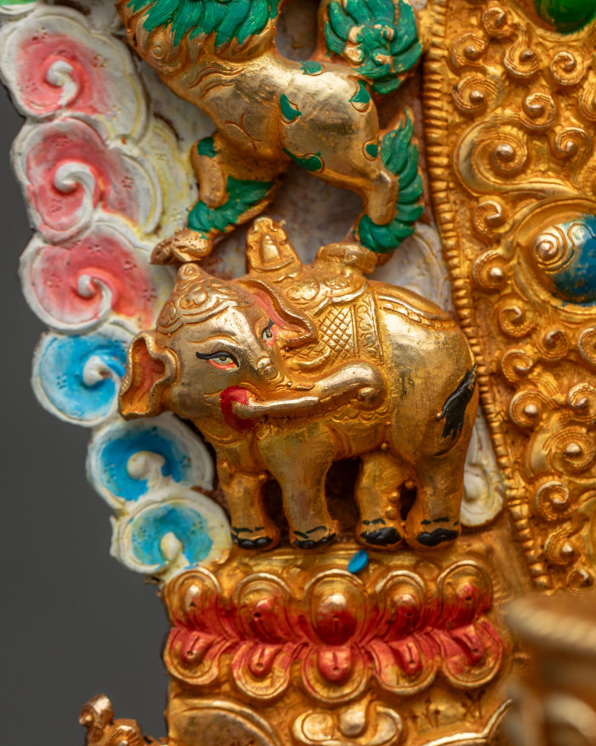 Close-up of gold-gilded elephant with painted detailing on Shakyamuni Buddha statue throne