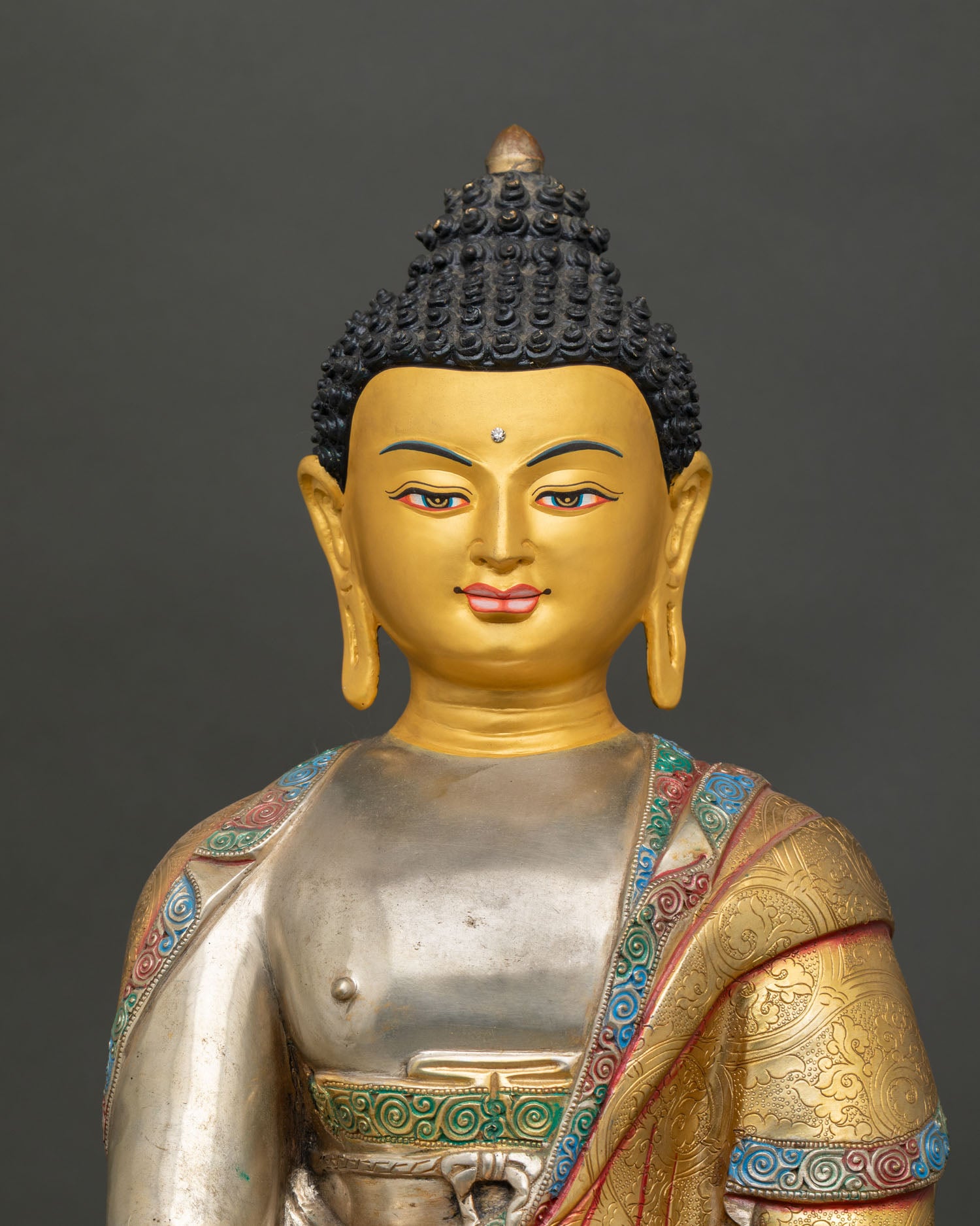 Close-up view of the gold-painted face of the Buddha Shakyamuni statue showing a serene expression