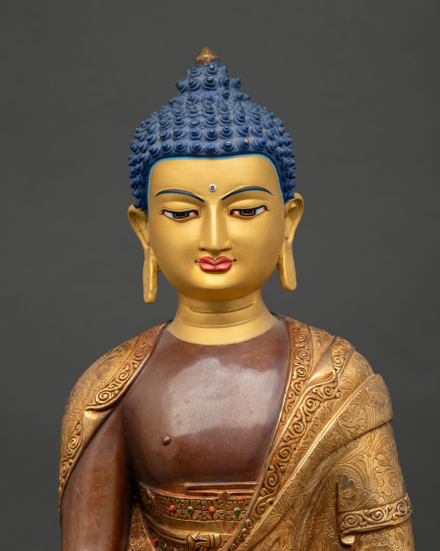 close up of gold painted face of shakayamuni buddha with deep blue eyes and peaceful expression