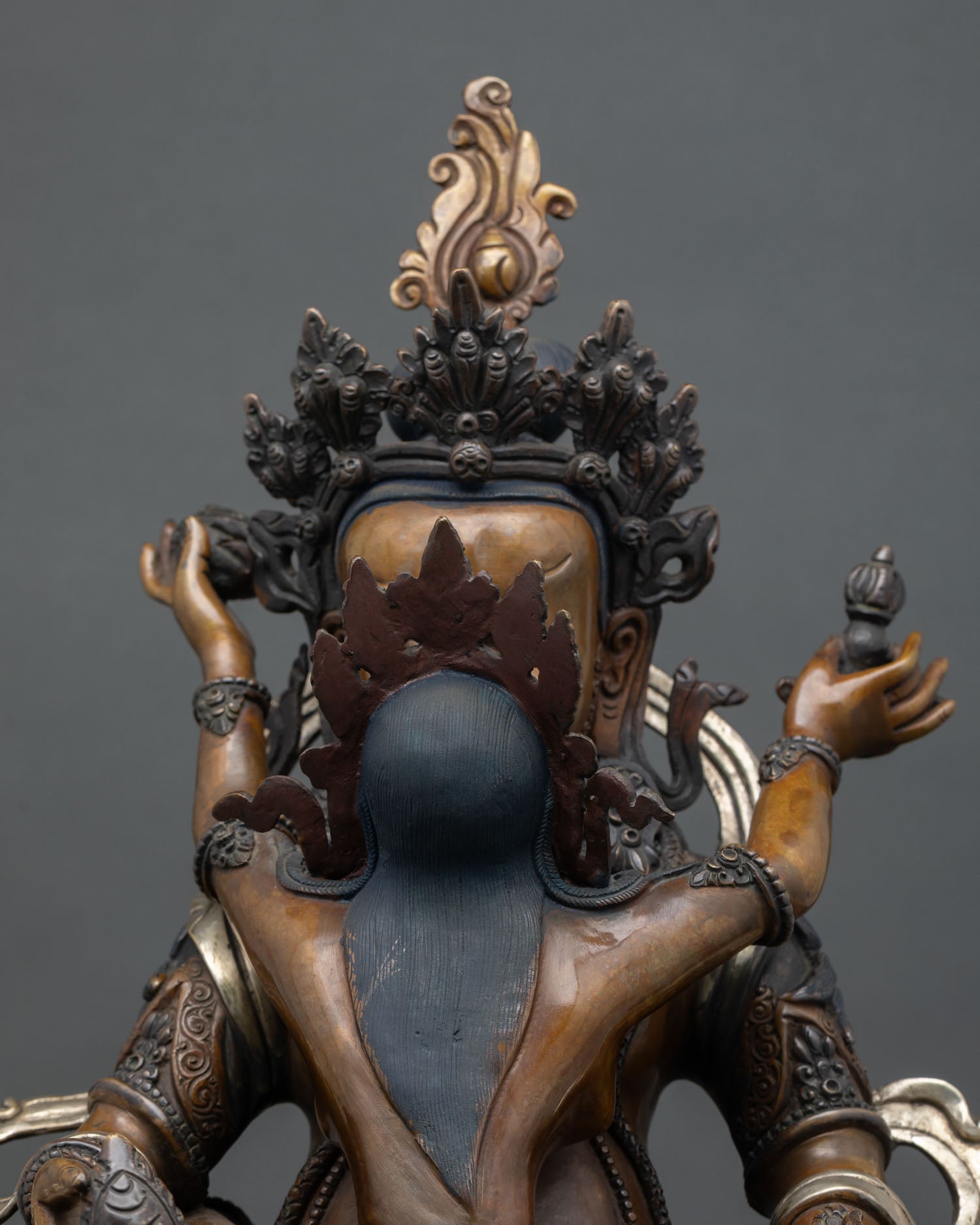 close-up of green dzambhala wealth deity statue with oxidized copper and lotus base