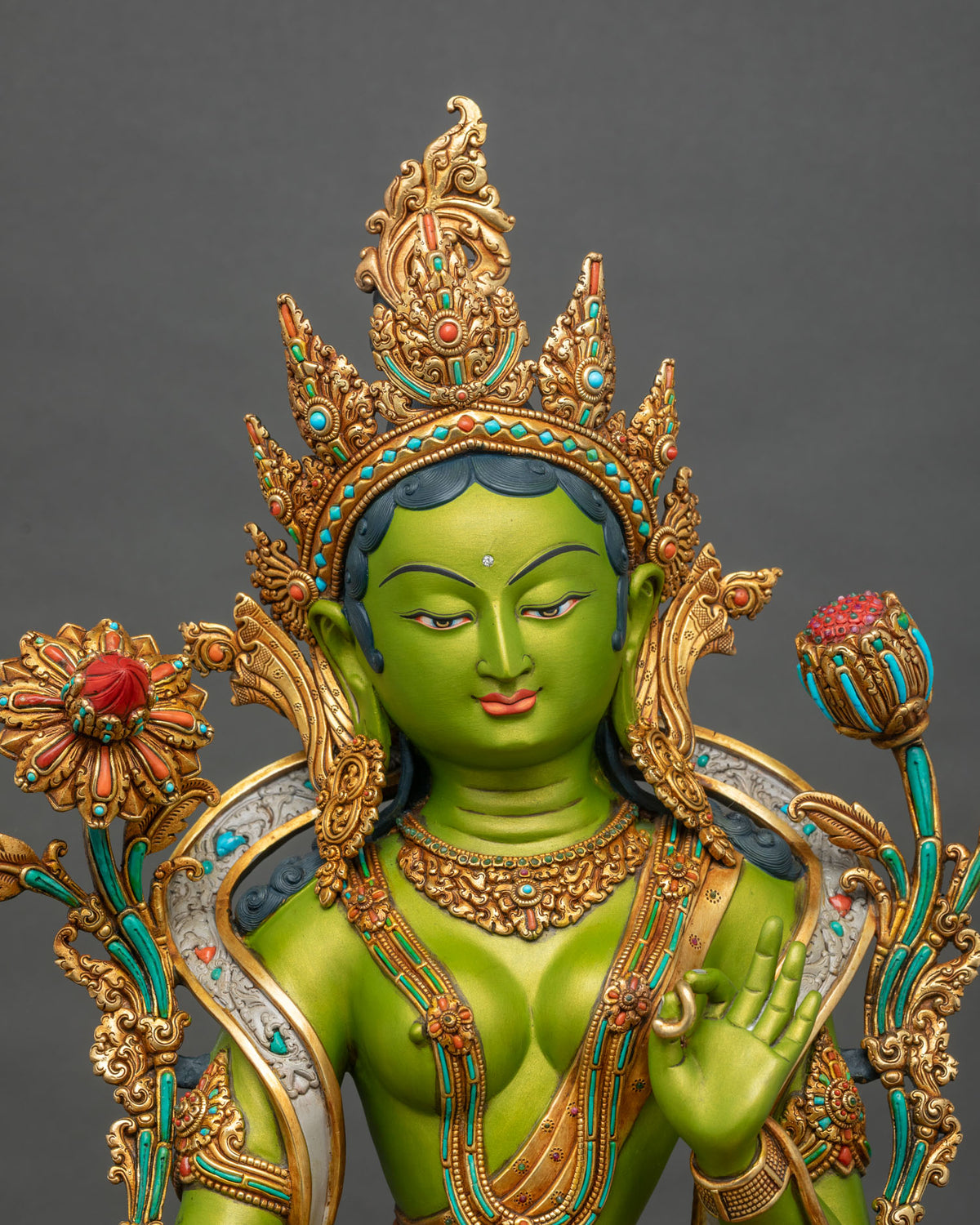 Close-up of Green Tara statue face and five-pointed crown set with turquoise and coral stones