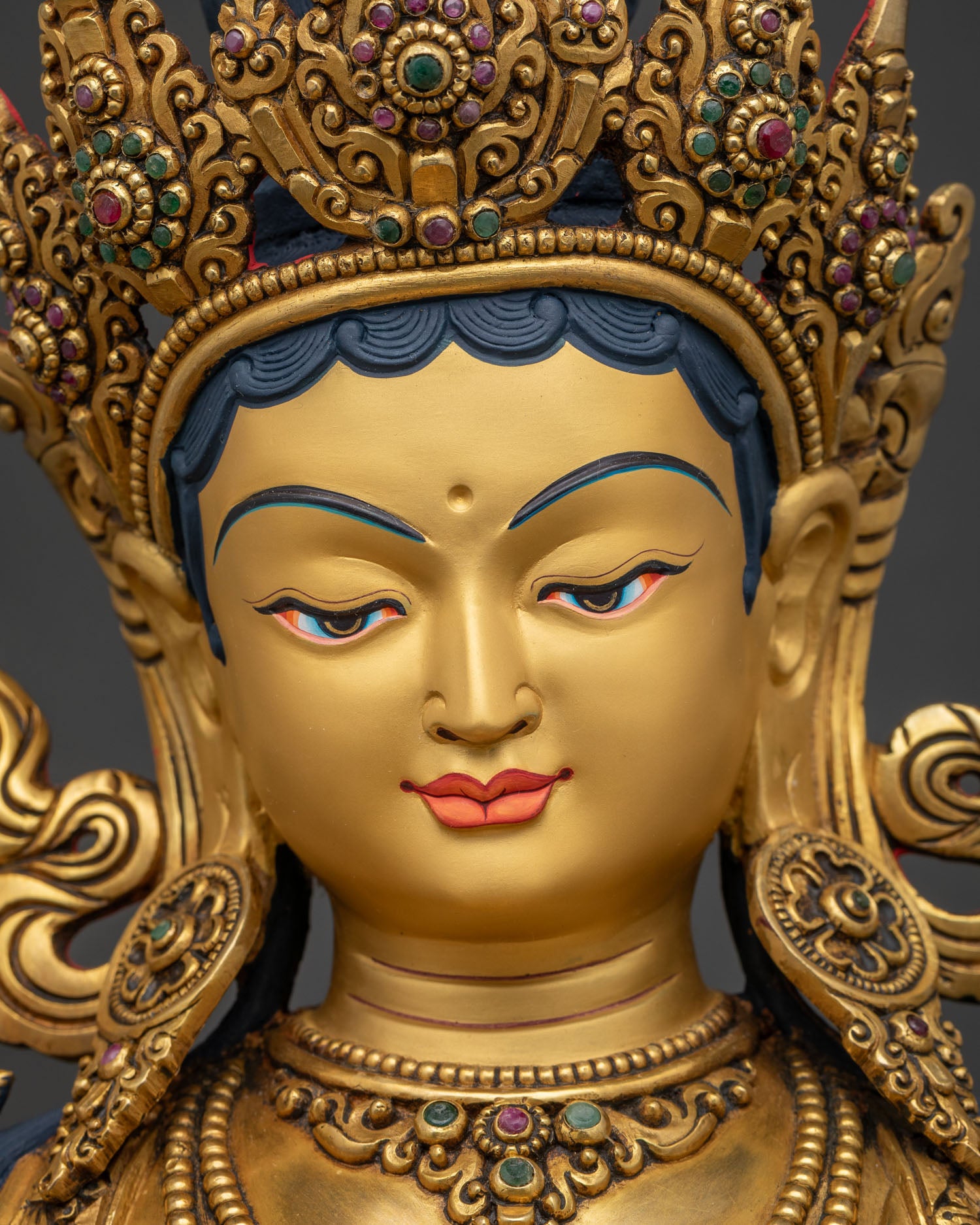 Close-up of Green Tara statue's gold-painted face with gentle serene expression