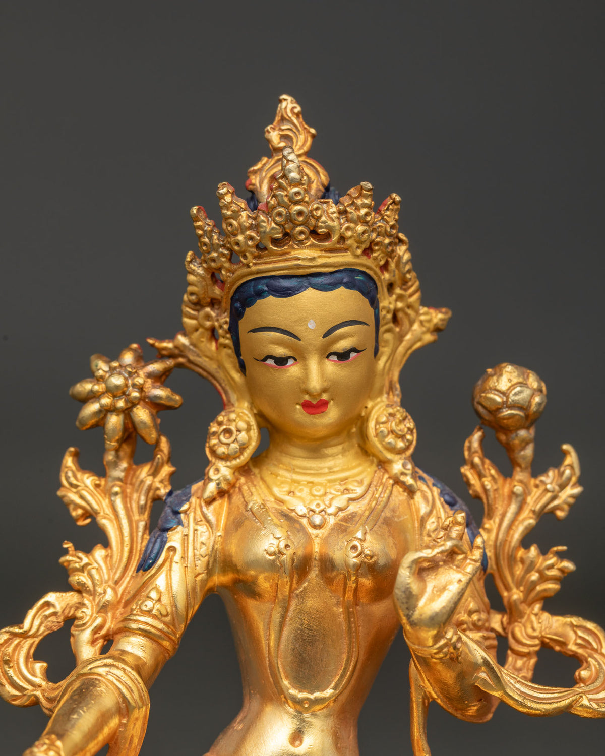 Close up of Green Tara statue with 24K gold painted face five point crown and serene expression.
