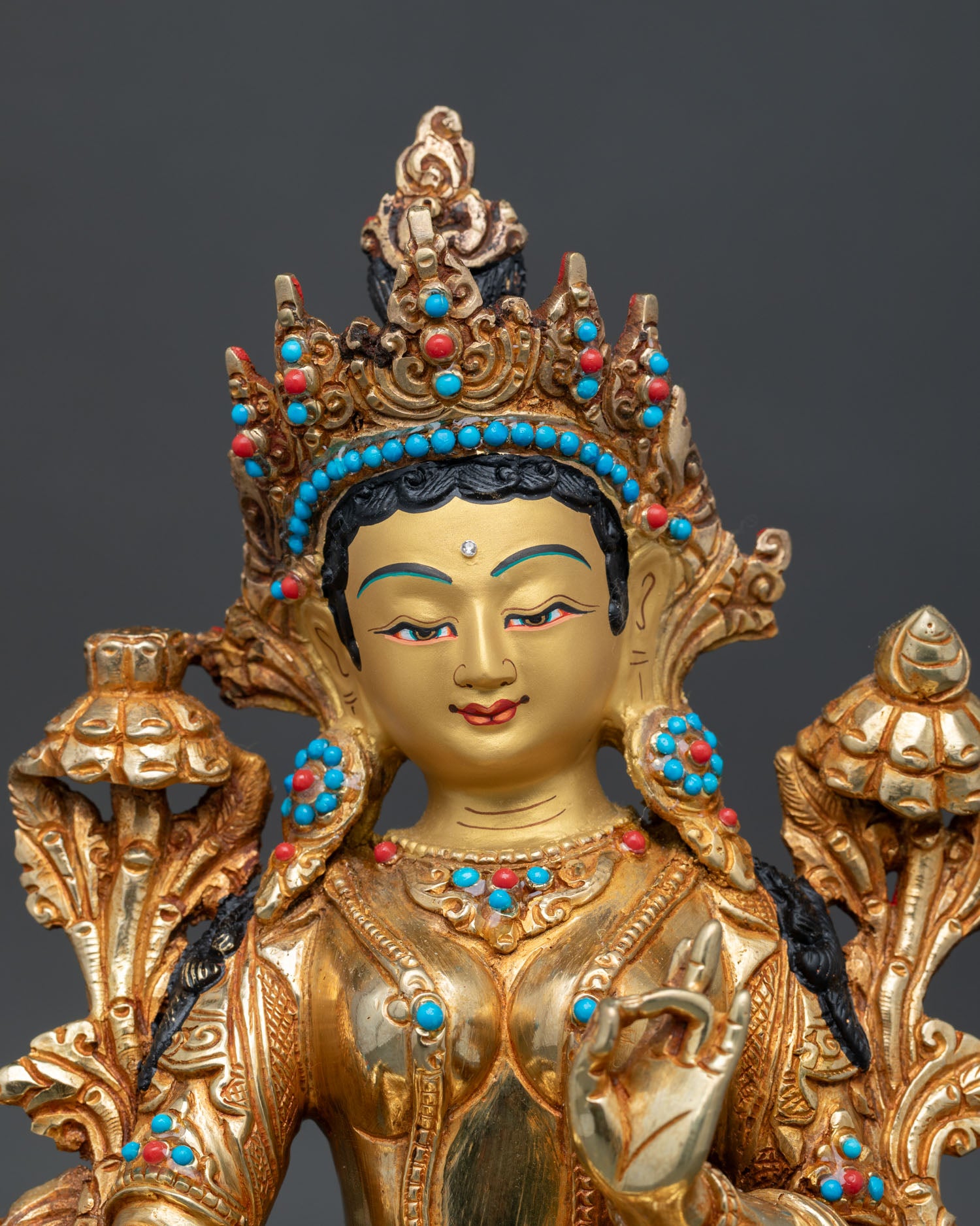 Close up of Green Tara statue with fire gilded details and semi precious stonesa