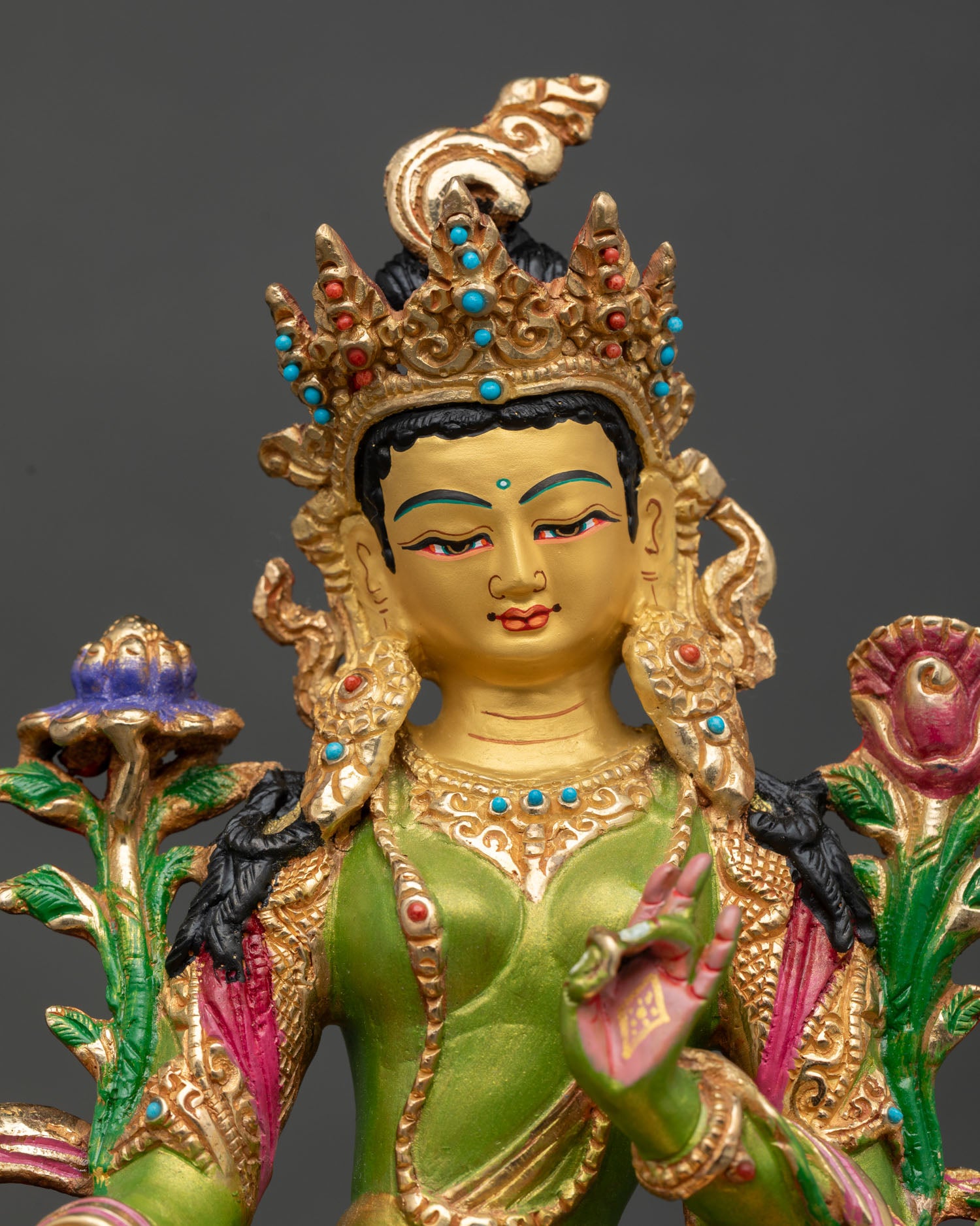 close up of green tara statue with gold-painted face and copper body artwork