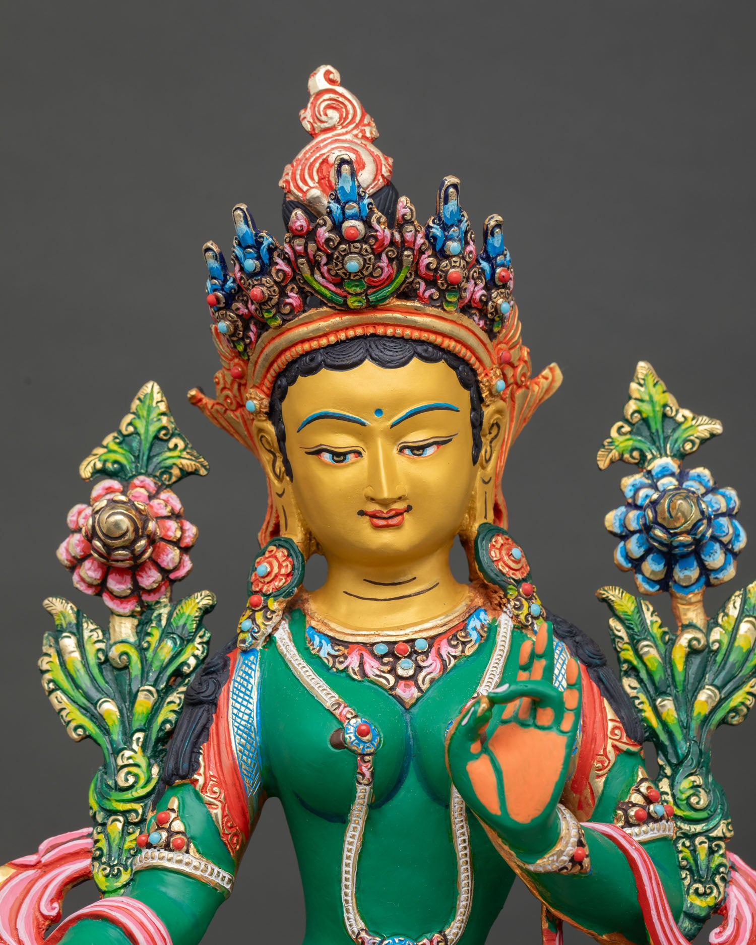 close-up of green tara statue with handpainted details and blue lotus
