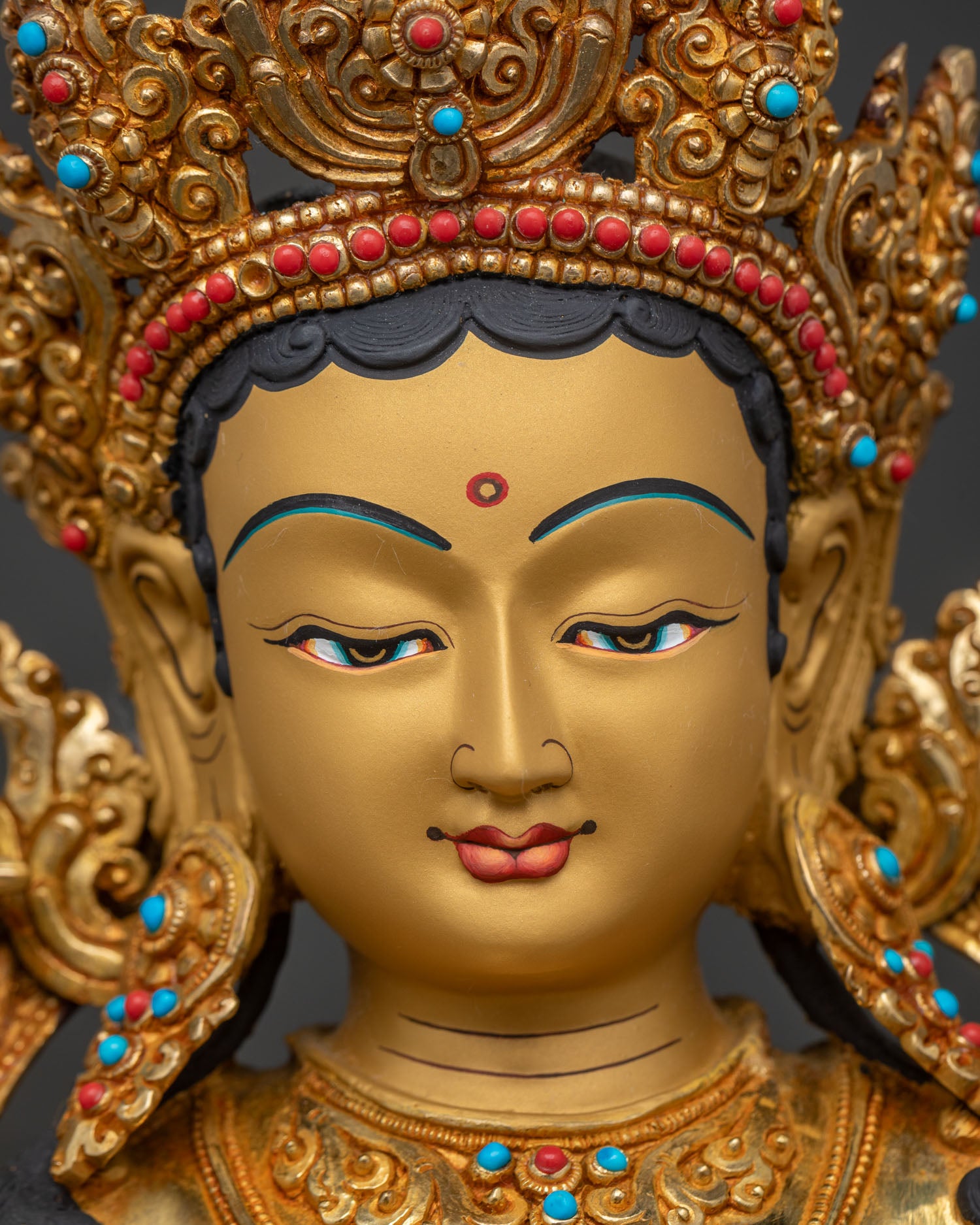 Close-up of Green Tara statue's serene gold-painted face and crown detail