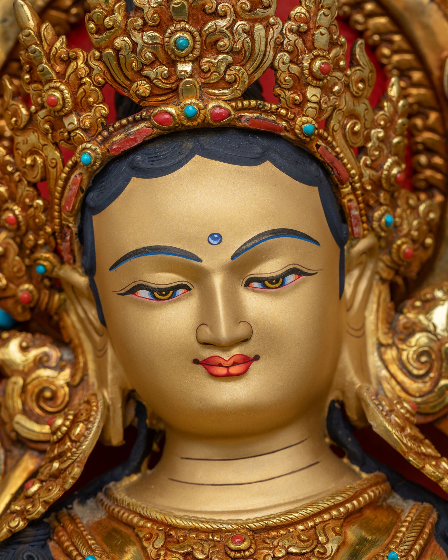 Close-up of Green Tara's gold-painted face with serene compassionate expression