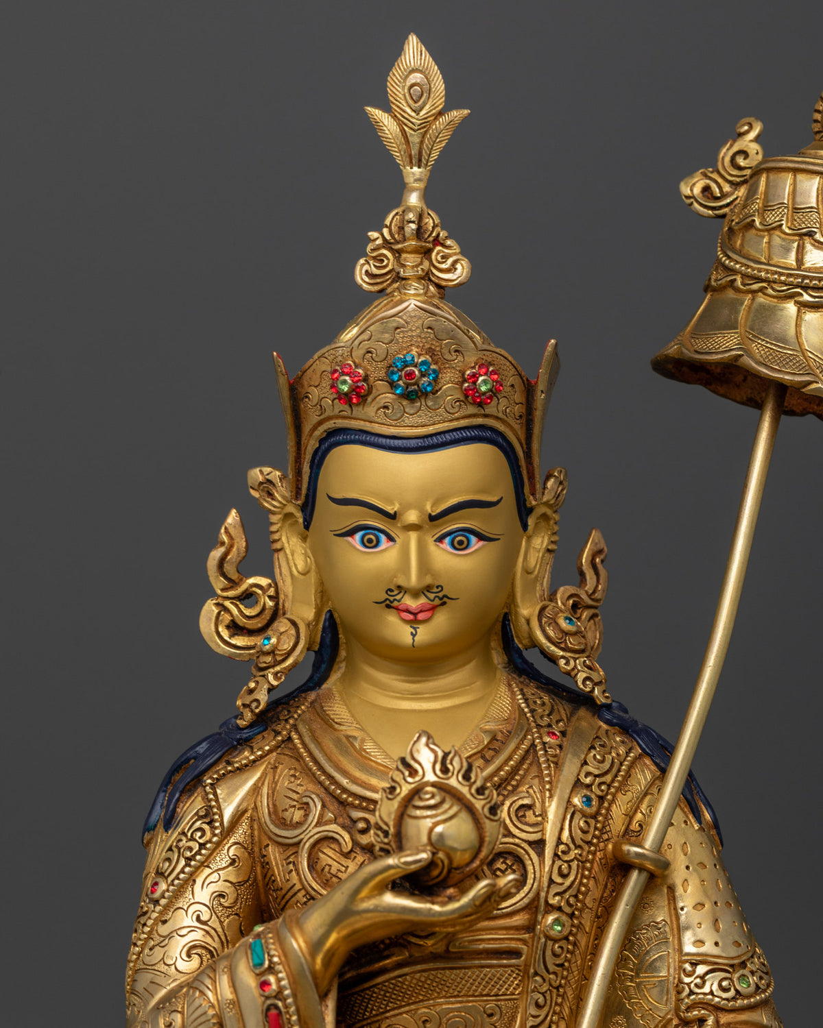 Close up of Guru Norlha statue with gold painted face jeweled ornaments and semi precious stones