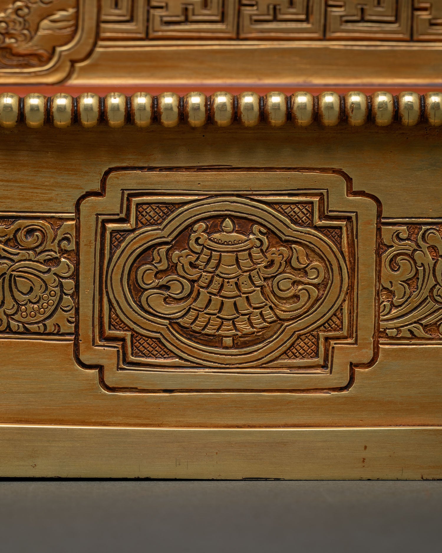 Close-up of hand-chased floral medallion carving on Dzambhala Statue throne