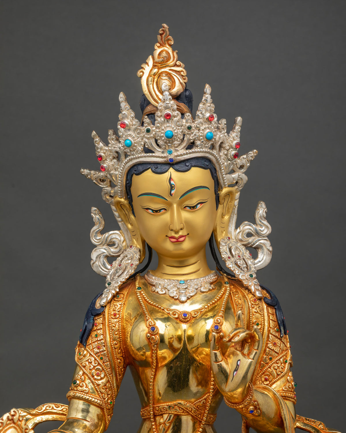 Close up of handcrafted Dukar Statue holding sacred mirror and silver parasol, gold-gilded copper