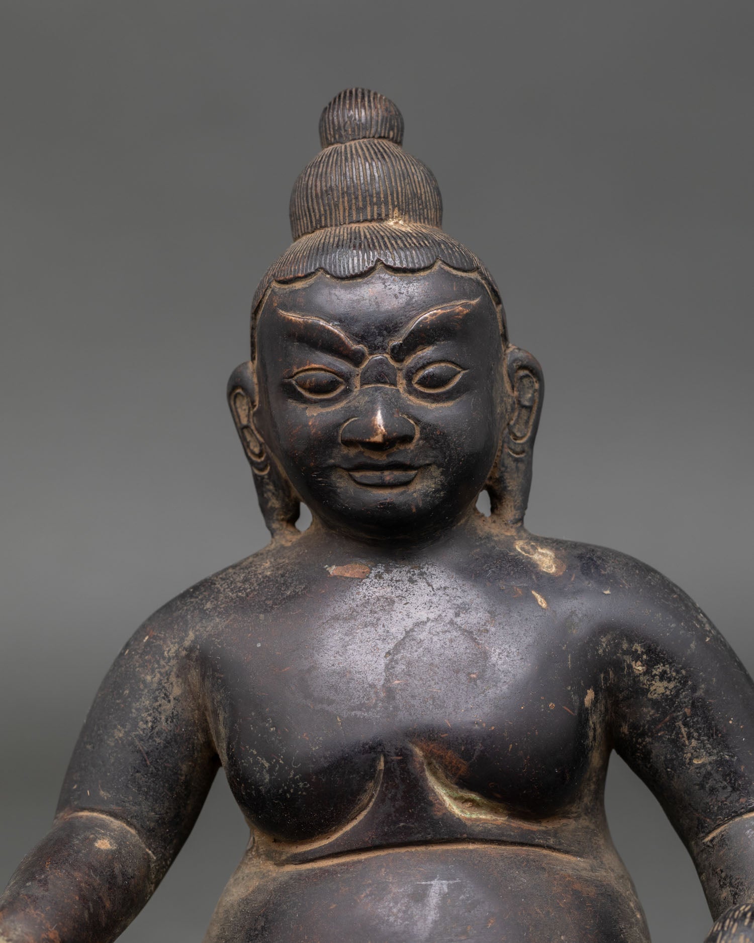 close up of handcrafted oxidized copper dzambhala statue with intricate buddhist details