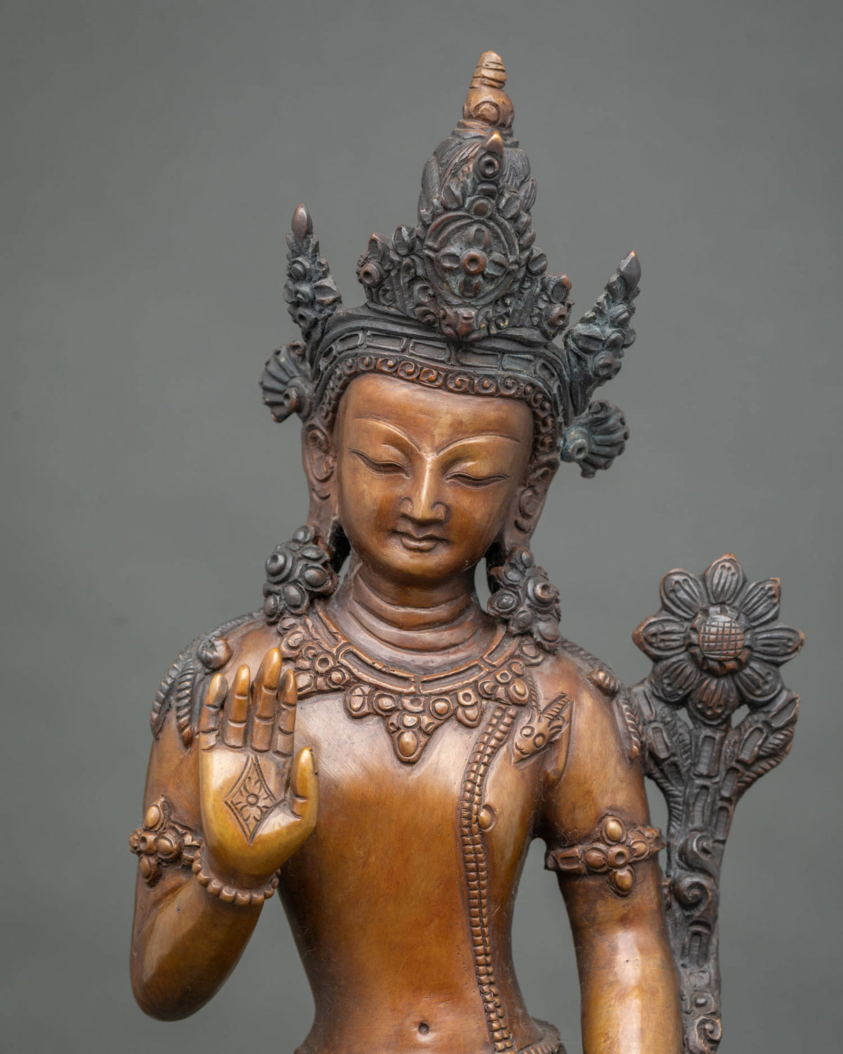 Close-up of handcrafted oxidized copper Lokeshvara statue showing crown, jewelry and lotus stem