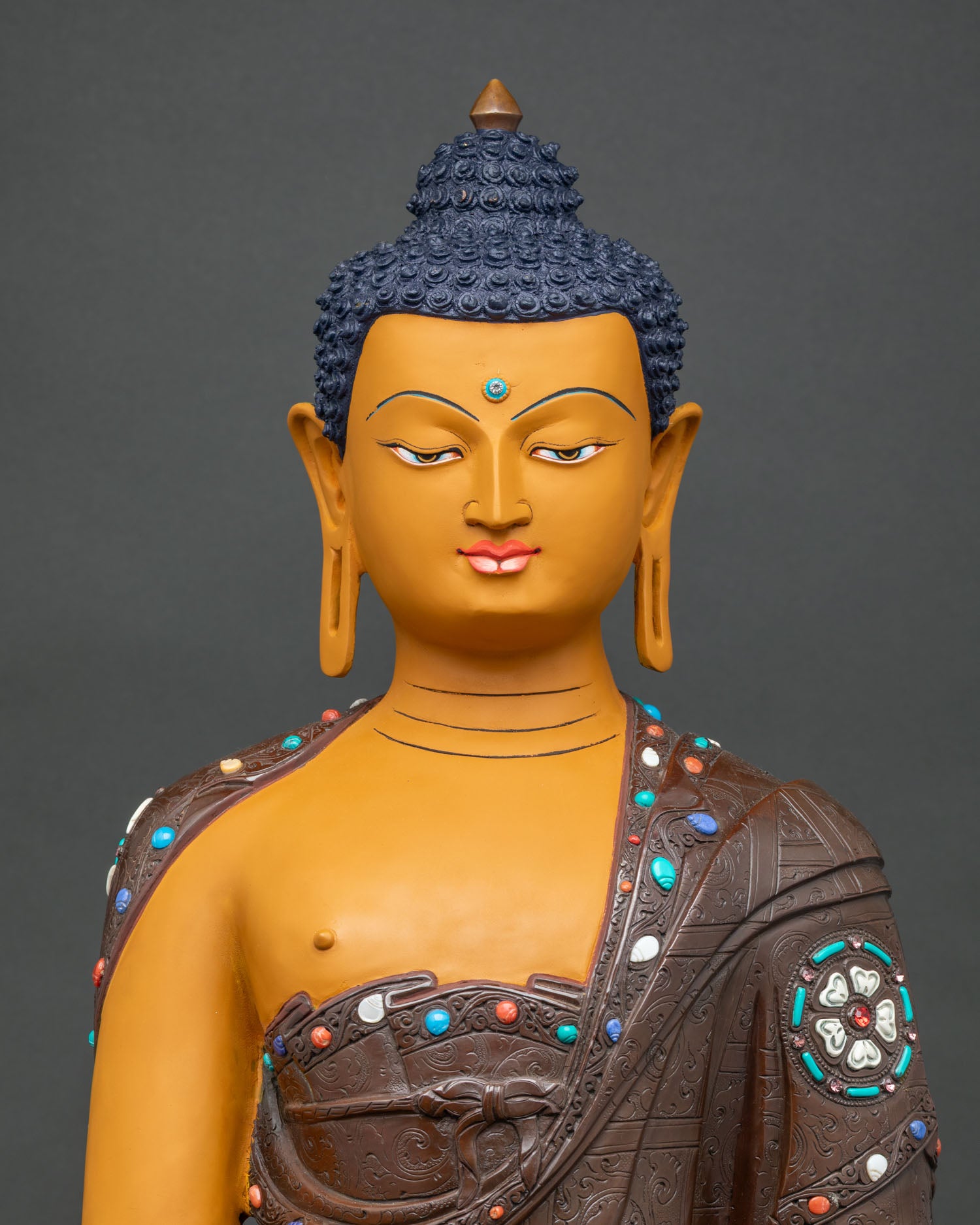 Close-up of handcrafted Shakyamuni Buddha statue with lotus base and engraved oxidized robe