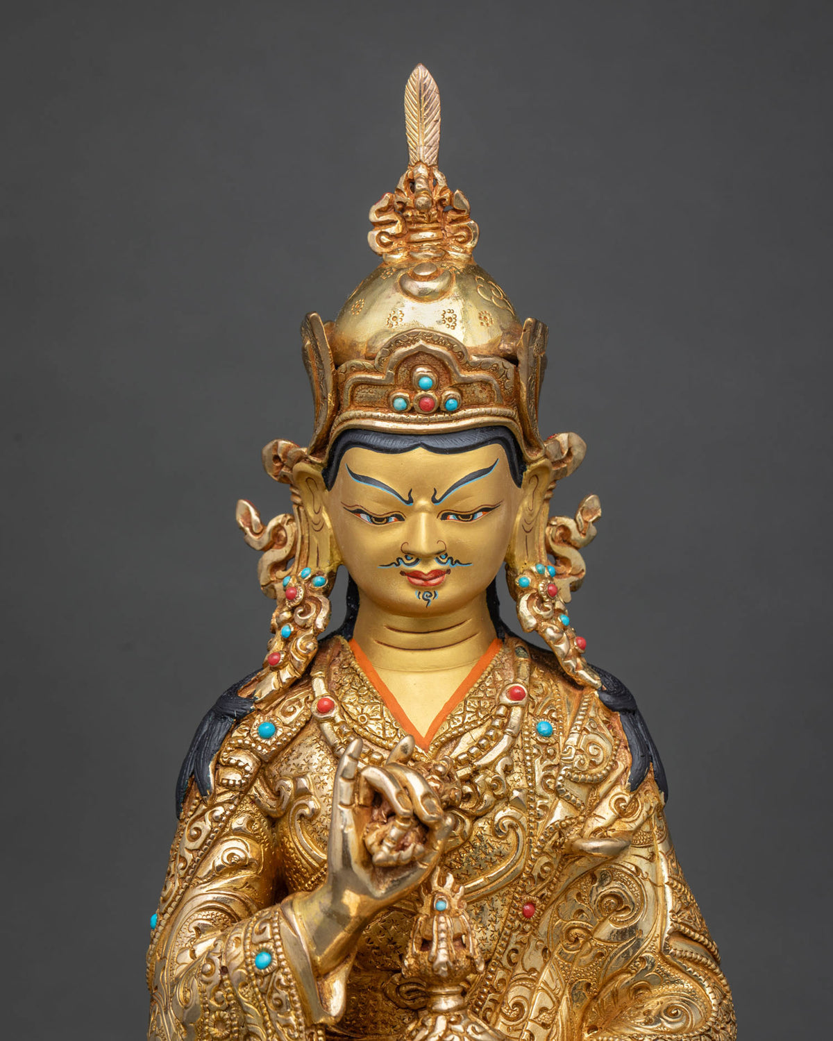 Close up of handcrafted Tsokye Dorje statue with fire-gilded robe and turquoise, coral inlay