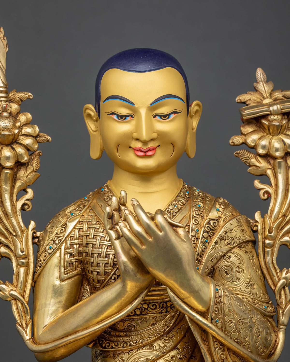 Close-up of Je Tsongkhapa face with dark blue scalp, serene smile and hands joined at chest