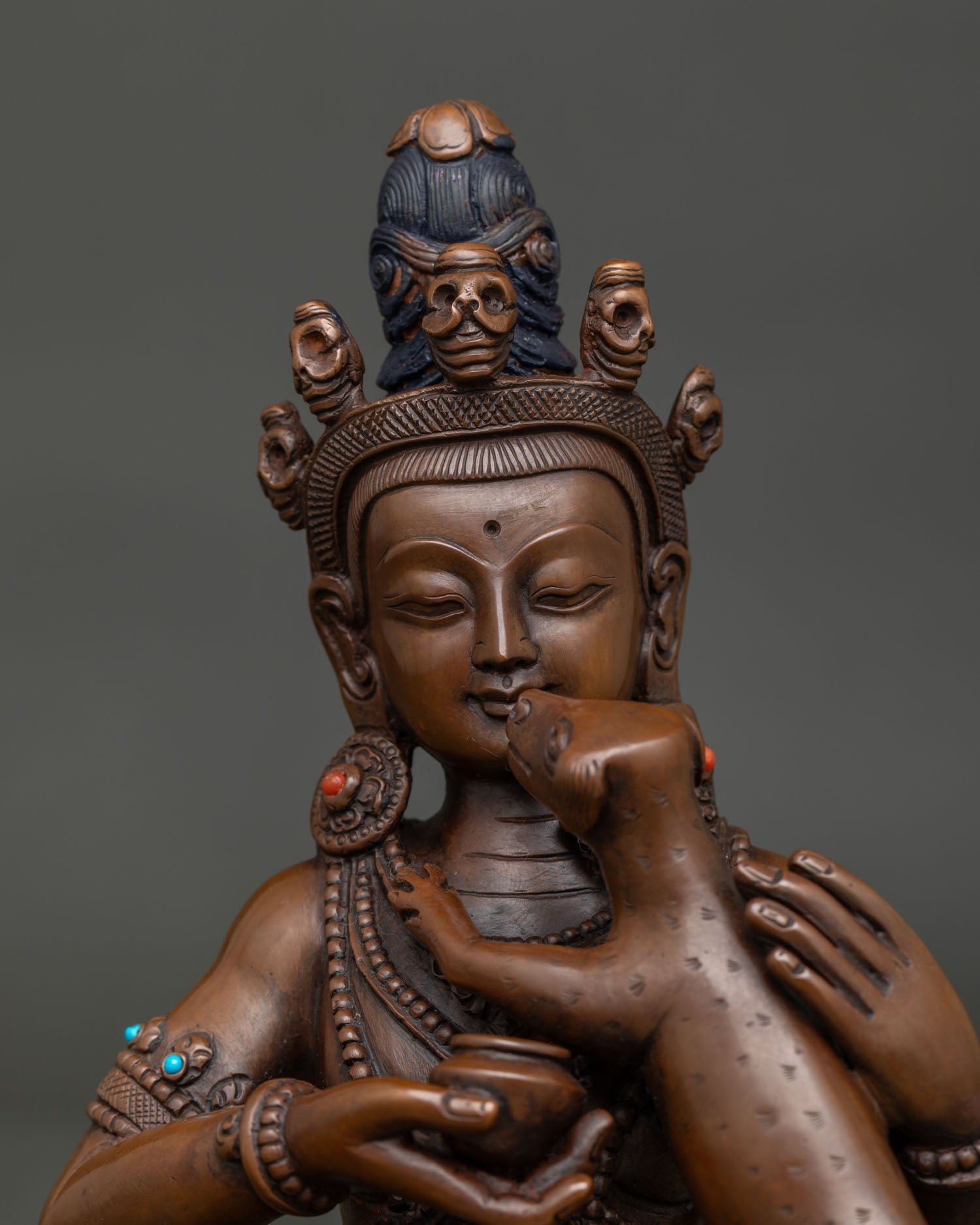 Close up of Kukkuripa Mahasiddha statue with turquoise & coral stone details and alms bowl