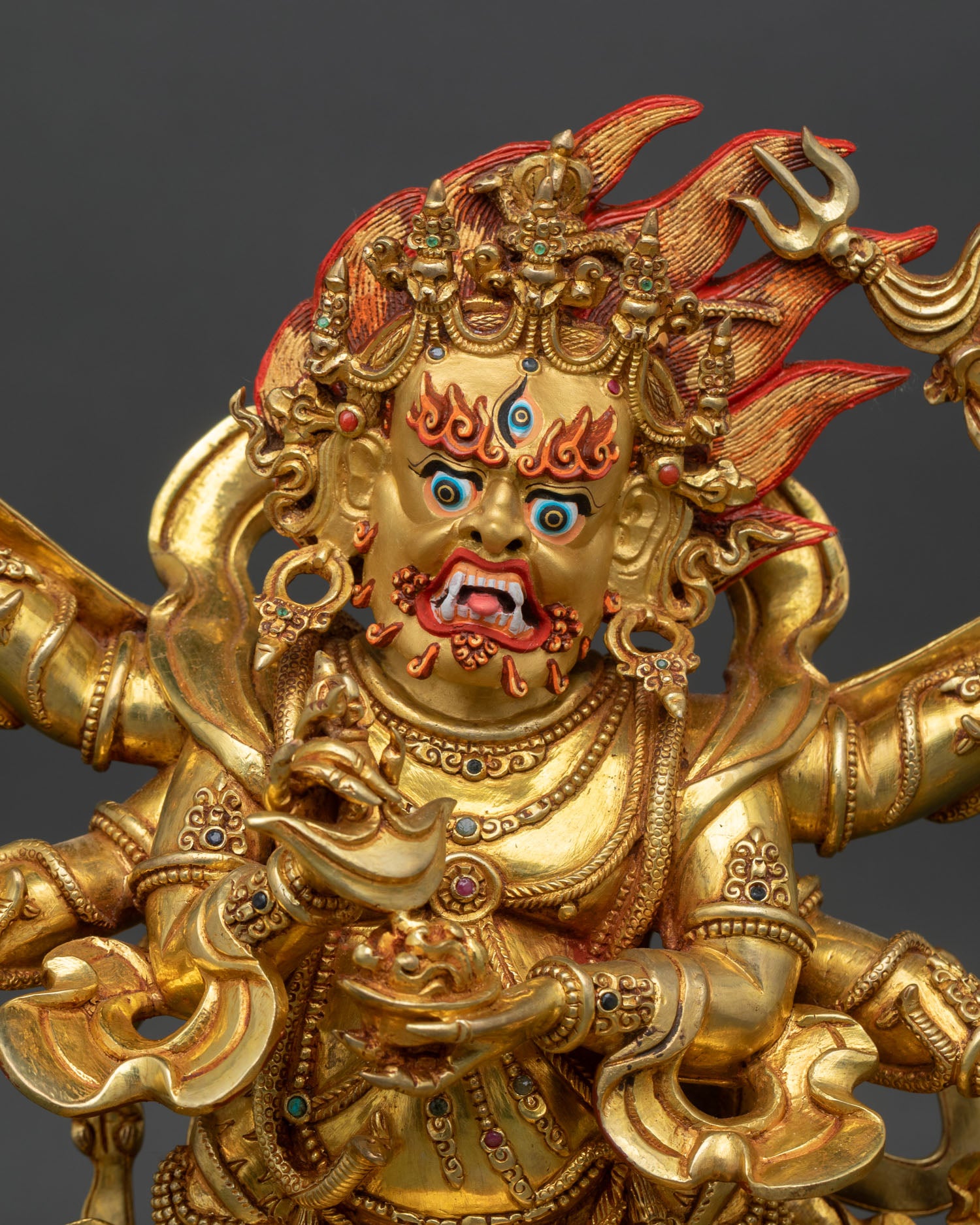Close up of Mahakala copper statue with gold painted face and semi precious stone detailing