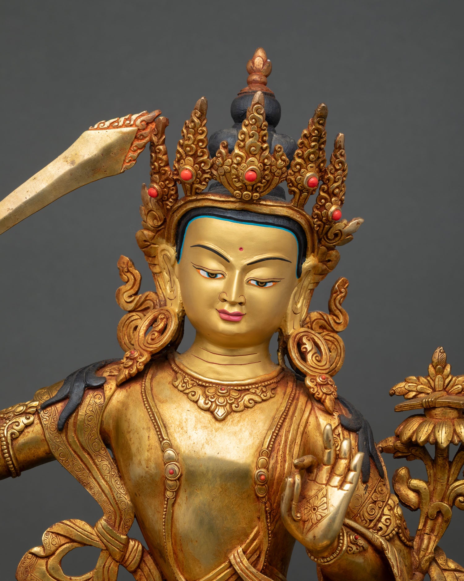 Close up of Manjushri Bodhisattva gold painted face with serene expression and intricate Himalayan artistry