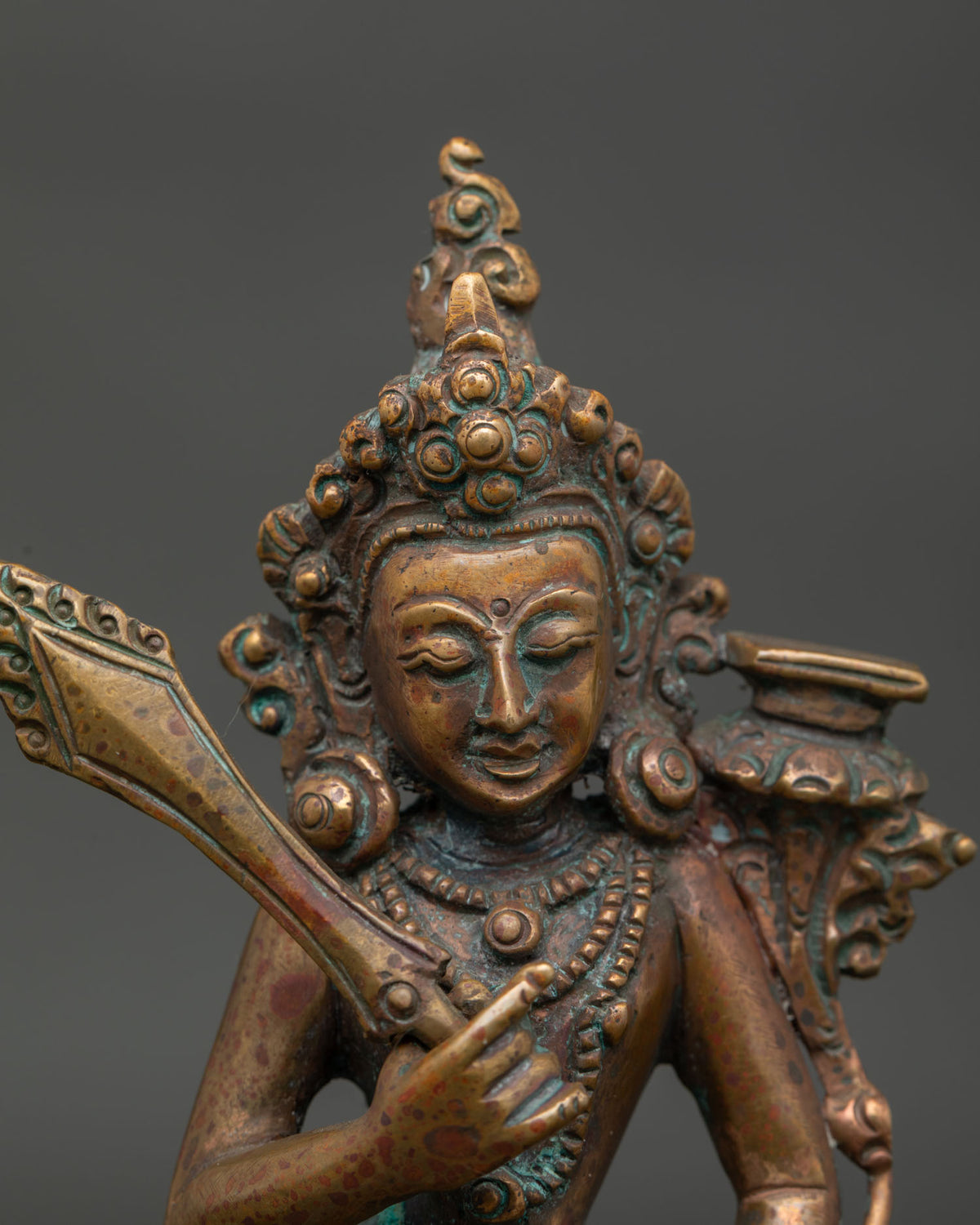 Close up of Manjushri bodhisattva statue showing serene face and ornate copper details.
