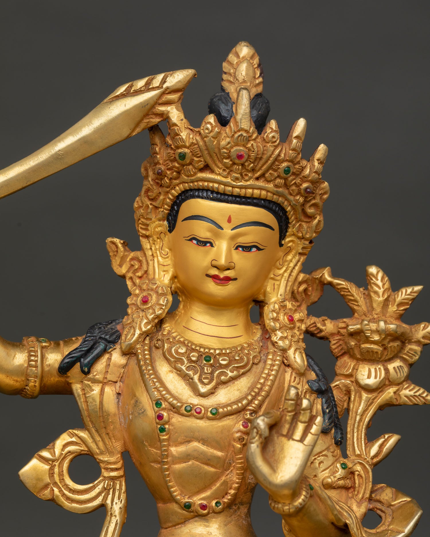 Close up of Manjushri statue showing 24k gold gilded face and intricate Himalayan Buddhist details
