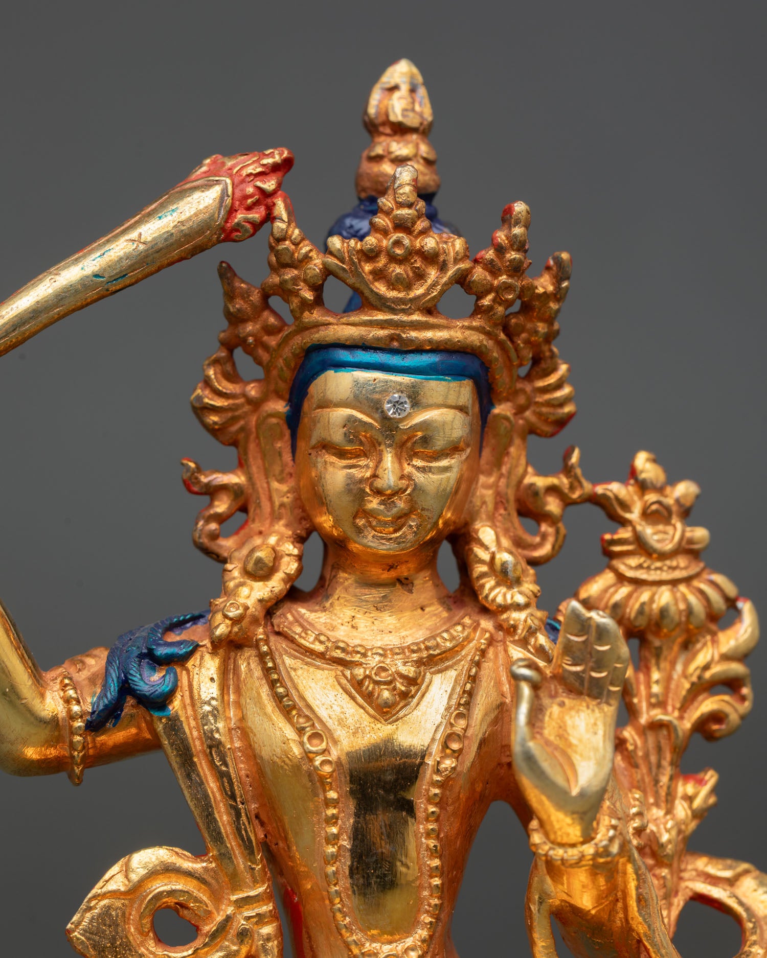 close up of manjushri statue with gold gilded crown and sacred sword