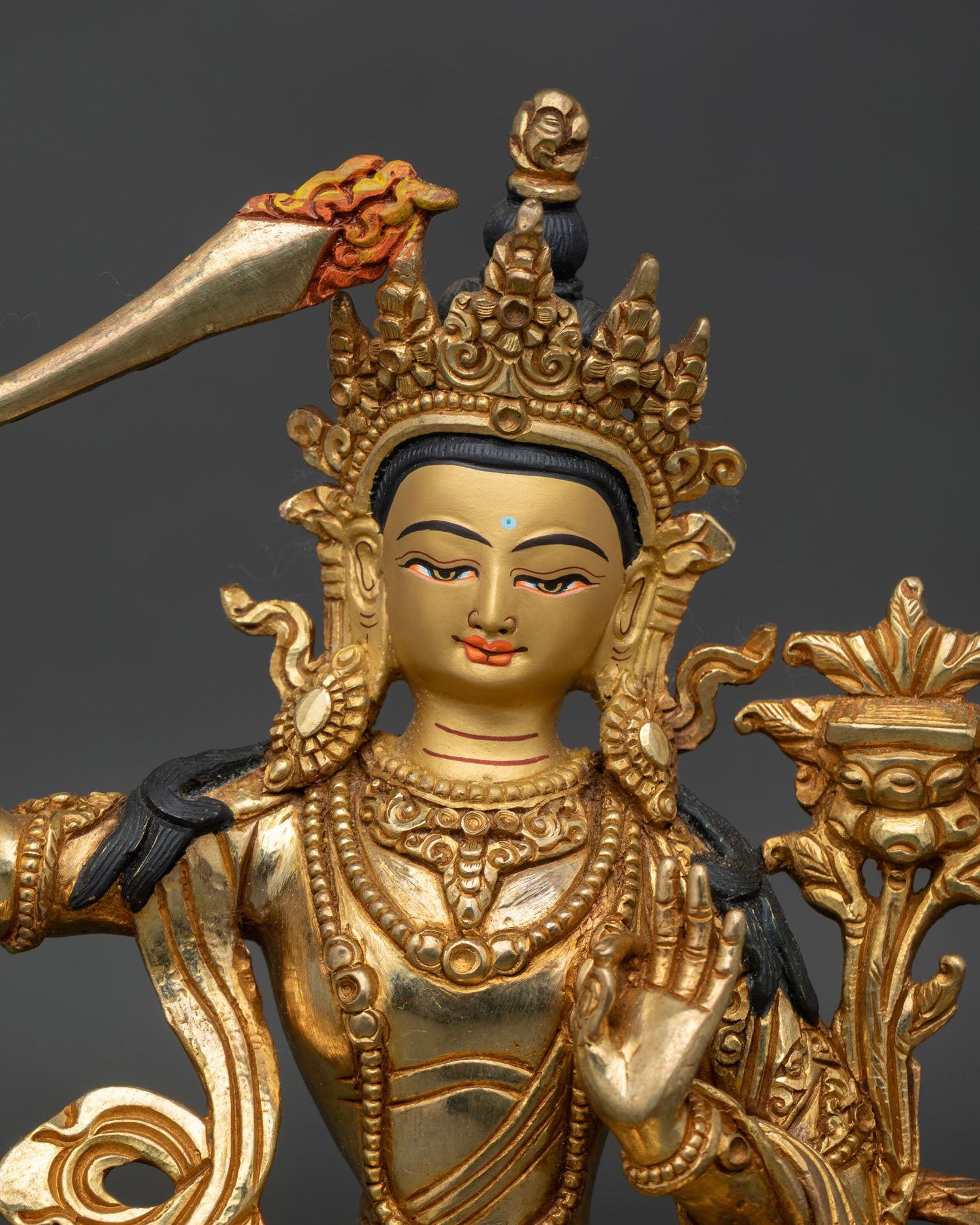 Close up of Manjushri wisdom deity statue, handcrafted copper with gold fire gilding details