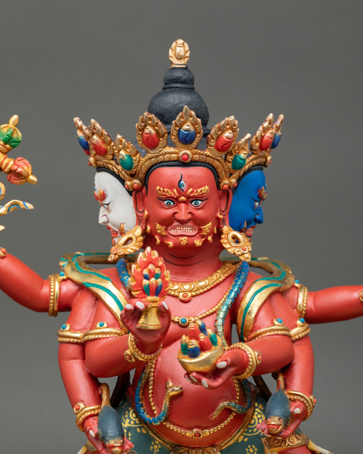Close up of Marpo Red Dzambhala statue gold painted face sacred ritual implements handcrafted Nepalese