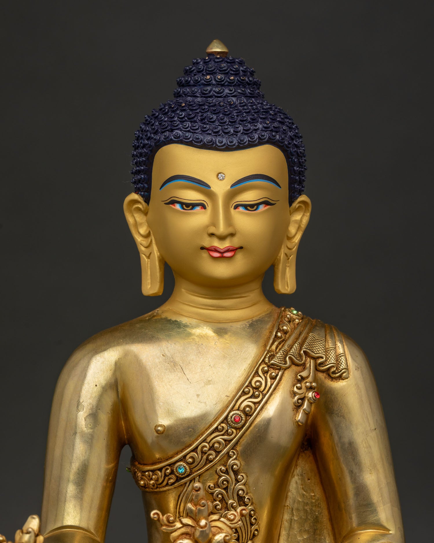 Close Up of Medicine Buddha Statue with Gold Painted Face and Sacred Stone Inlays