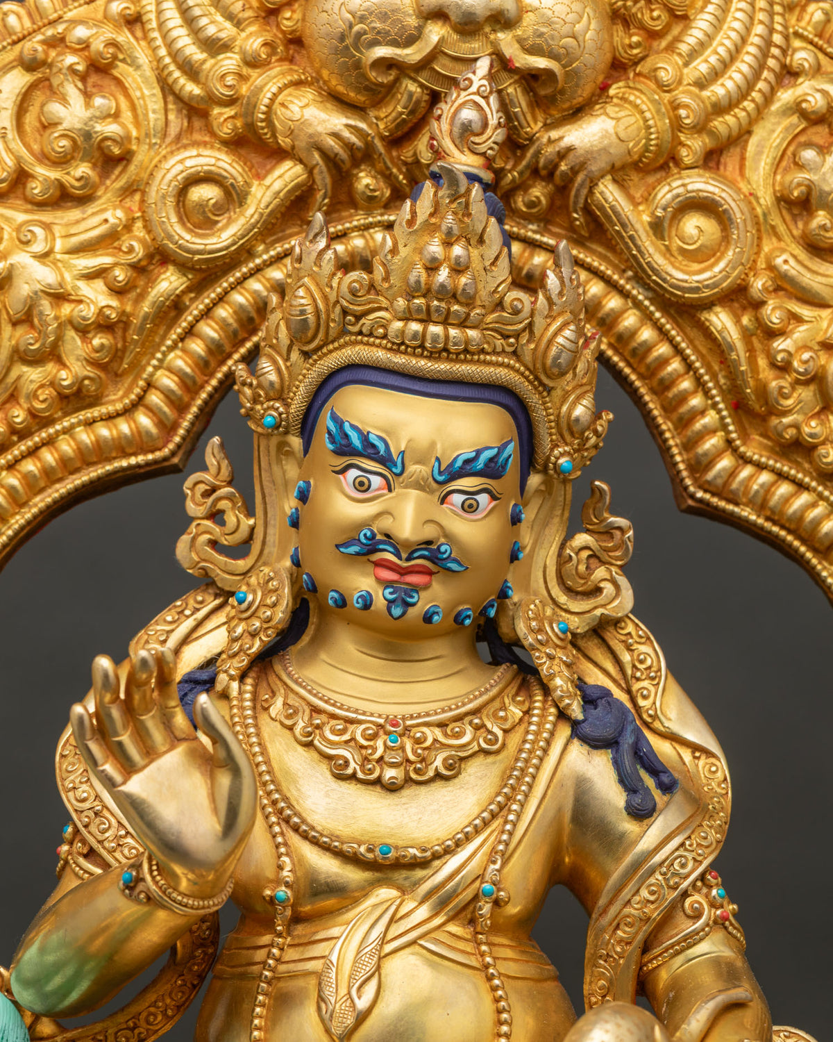 Close up of Namtoshe Vaishravana statue in 24K gold with flame crown, turquoise inlay and raised hand