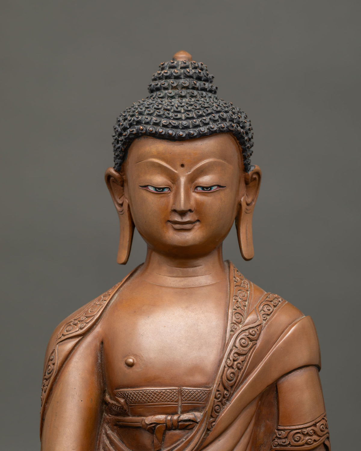 Close up of oxidized copper Shakyamuni Buddha statue seated on a lotus pedestal