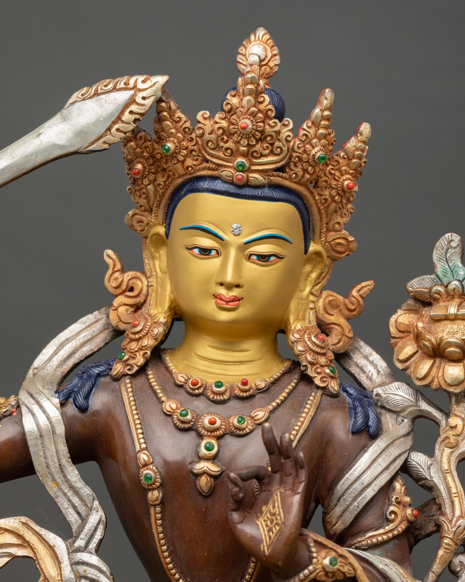 close up of oxidized manjushri statue with gold gilded details and sacred symbols