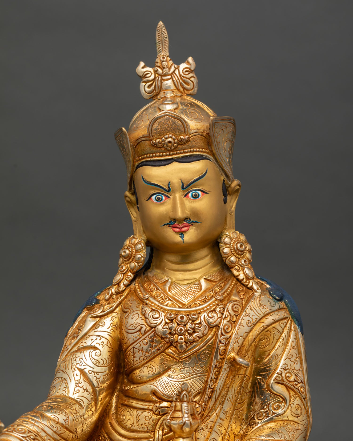 Close up of Padmasambhava Guru Rinpoche semi wrathful face with intricate floral carved details and gold finish
