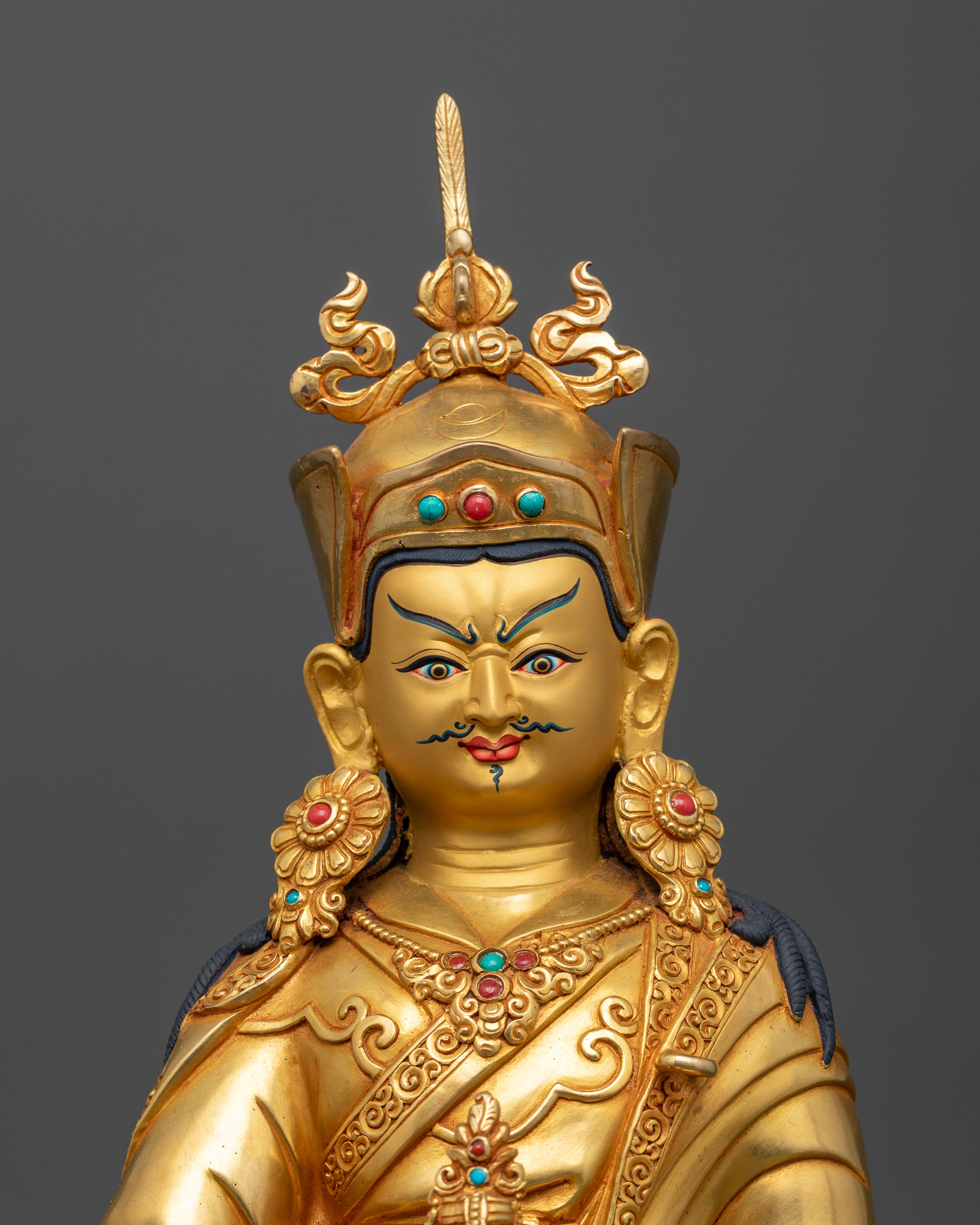 Close up of Padmasambhava Statue, showing serene gold painted face and Himalayan craftsmanship