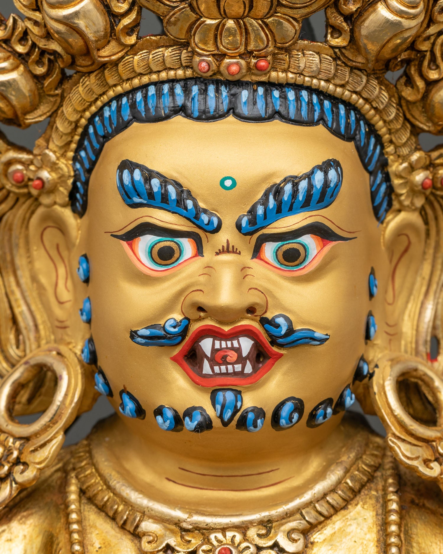 Close up of Red Dzambhala face gold painted beard and intricate copper details handmade Patan Nepal