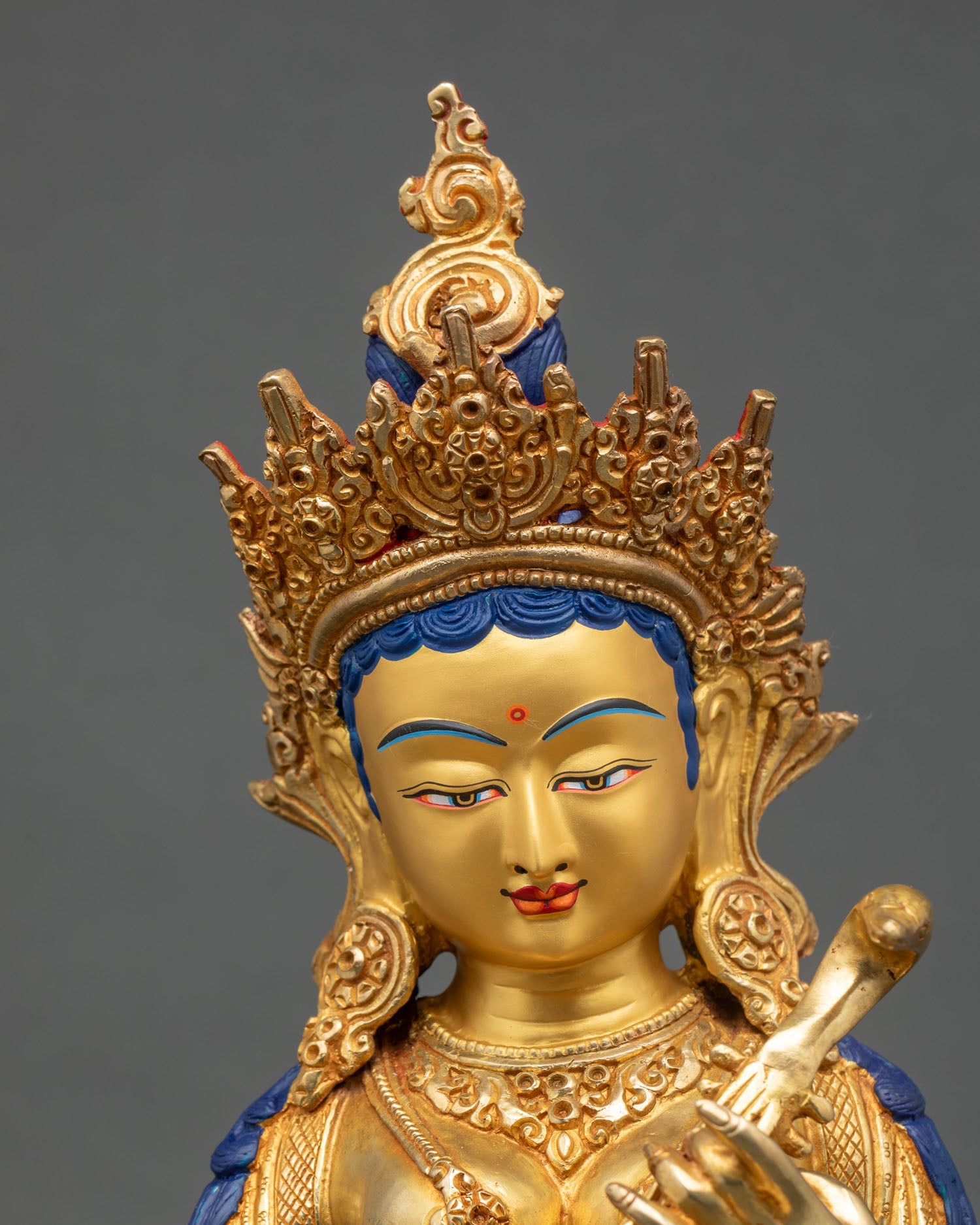 Close-up of Saraswati statue showing intricate gold gilding and jewelry details