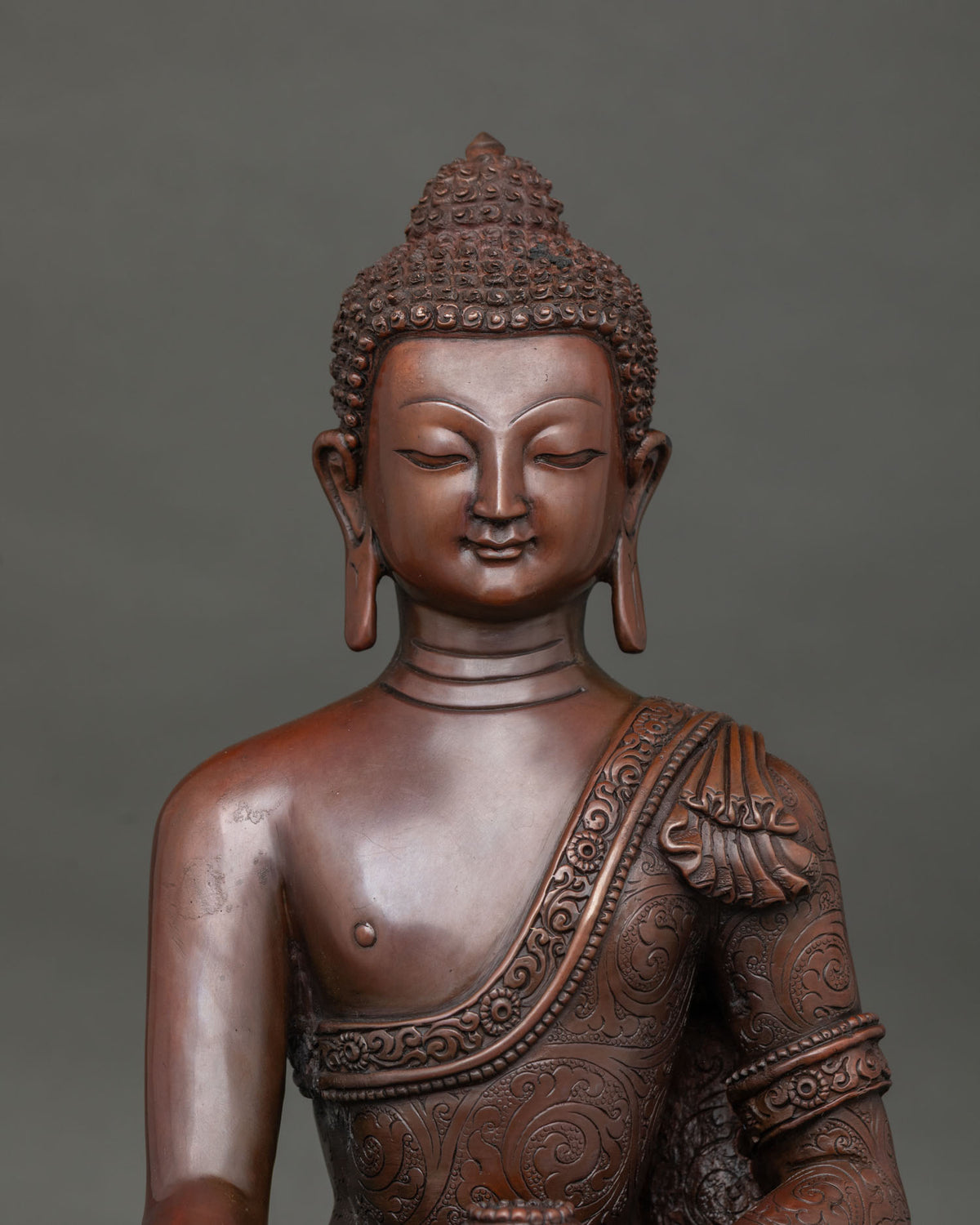 Close up of Shakyamuni buddha face floral motif robe and oxidized copper details.