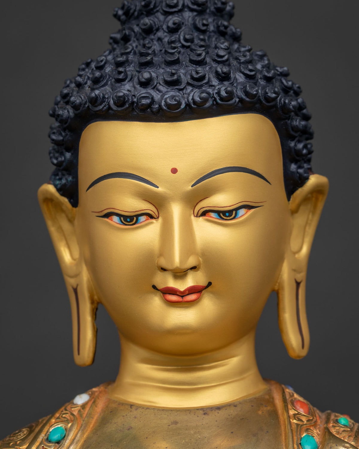 Close-up of Shakyamuni Buddha face, gold-gilded features with hand-painted eyes
