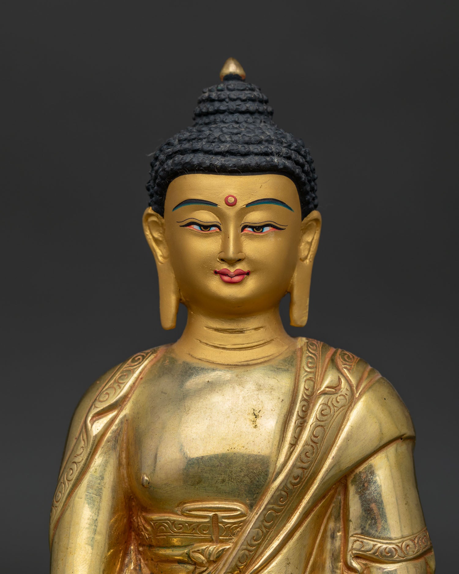 Close up of Shakyamuni Buddha gold painted face with handcarved monk's robe.