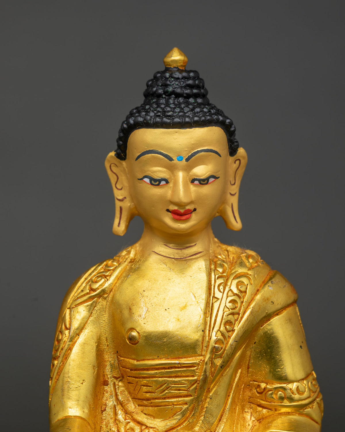 Close-up of Shakyamuni Buddha statue's gold-painted face with finely carved black hair