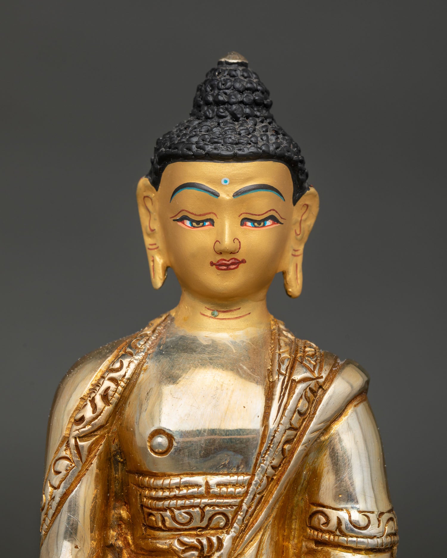 Close-up of Shakyamuni Buddha Statue showing earth-touching mudra and gold-painted face