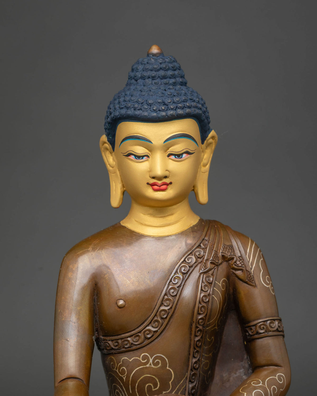 Close up of Shakyamuni Buddha statue with gold-painted face and silver-plated robe scrollwork