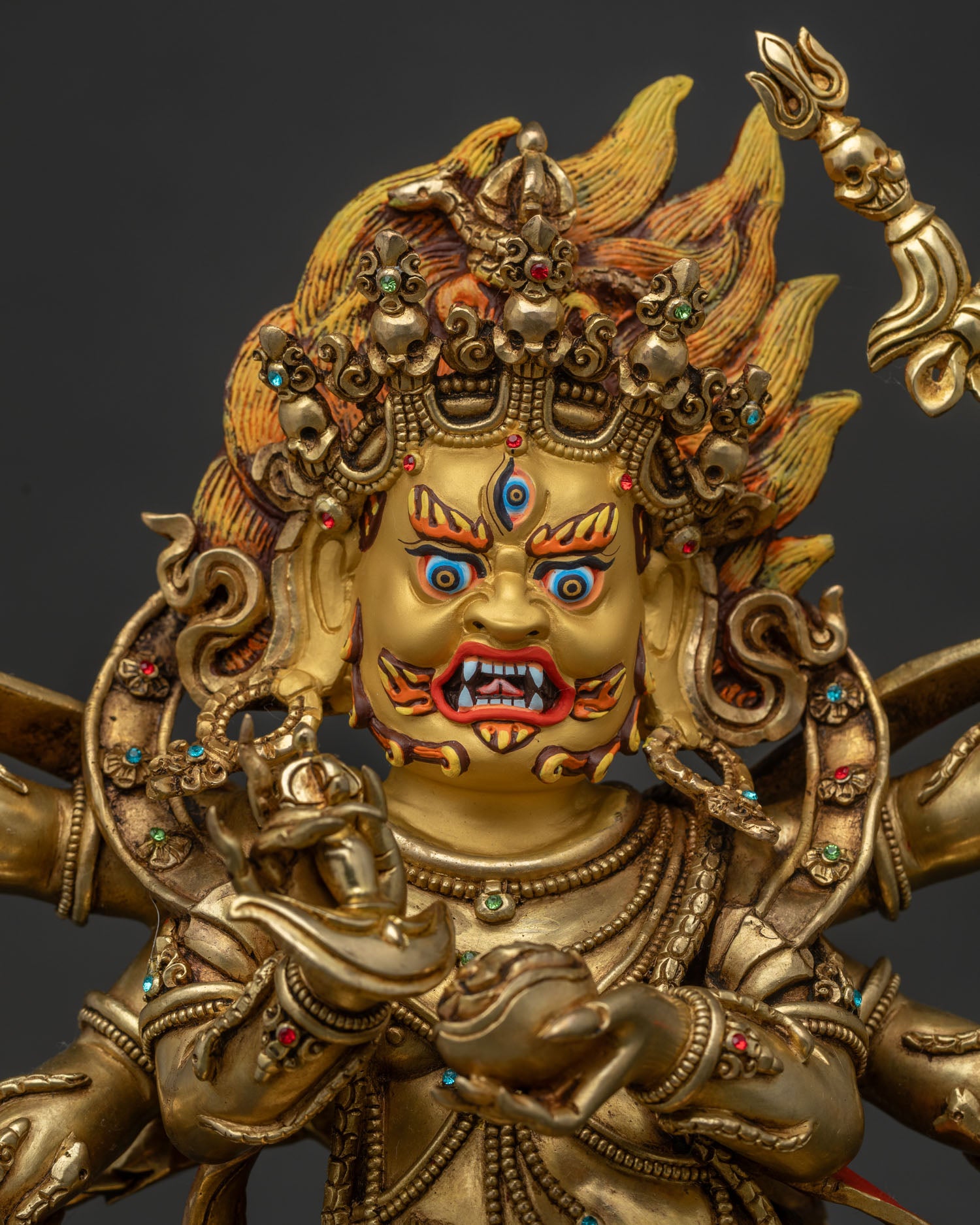 close up of six armed mahakala statue holding skull cup and trident