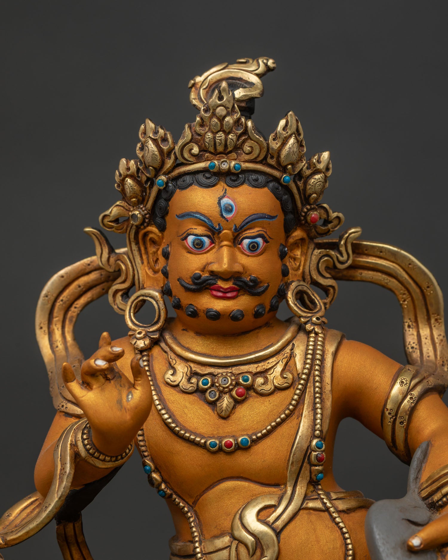 Close-up of solid copper Namtoshe wealth deity statue with gold gilding and gem inlays
