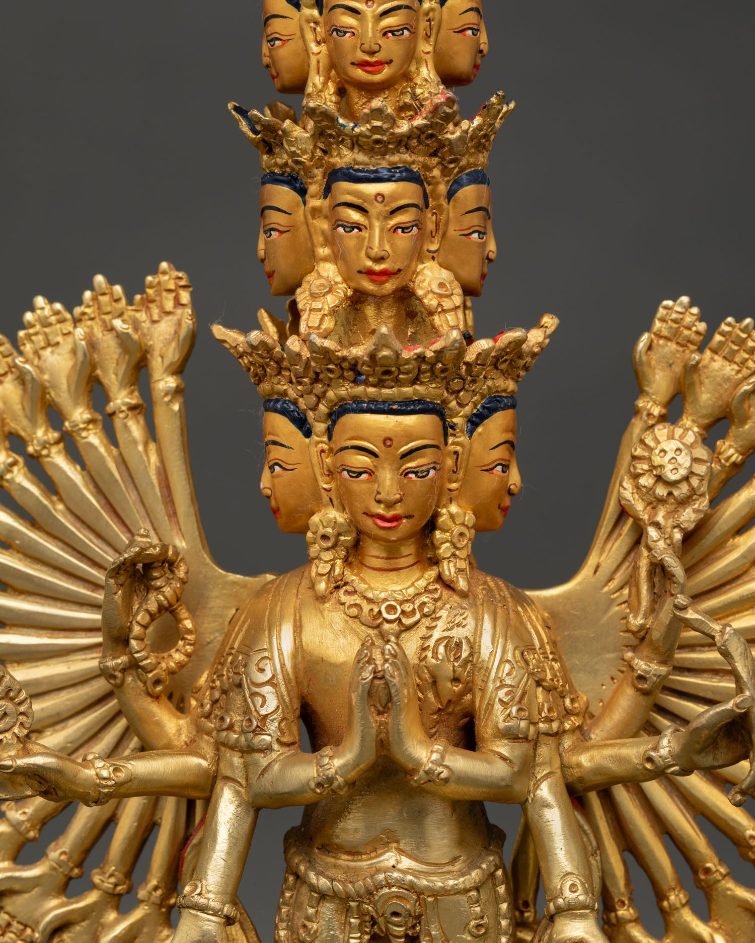 close up of thousand armed chenrezig statue with intricate gold fire gilding details