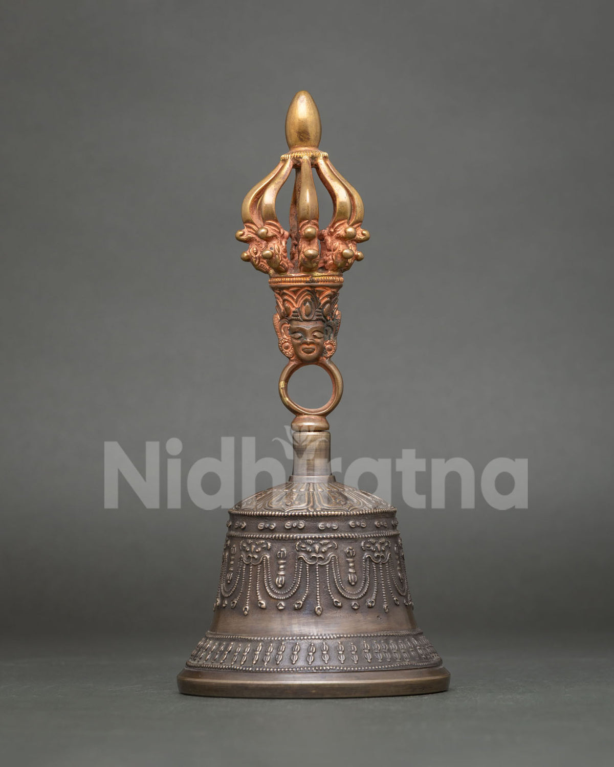 Close up of Tibetan Buddhist bell with copper handle, sacred deities, and intricate symbolic motifs